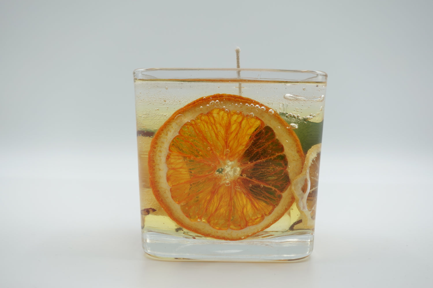 Refillable tangerine candle with dried orange slice in clear glass jar