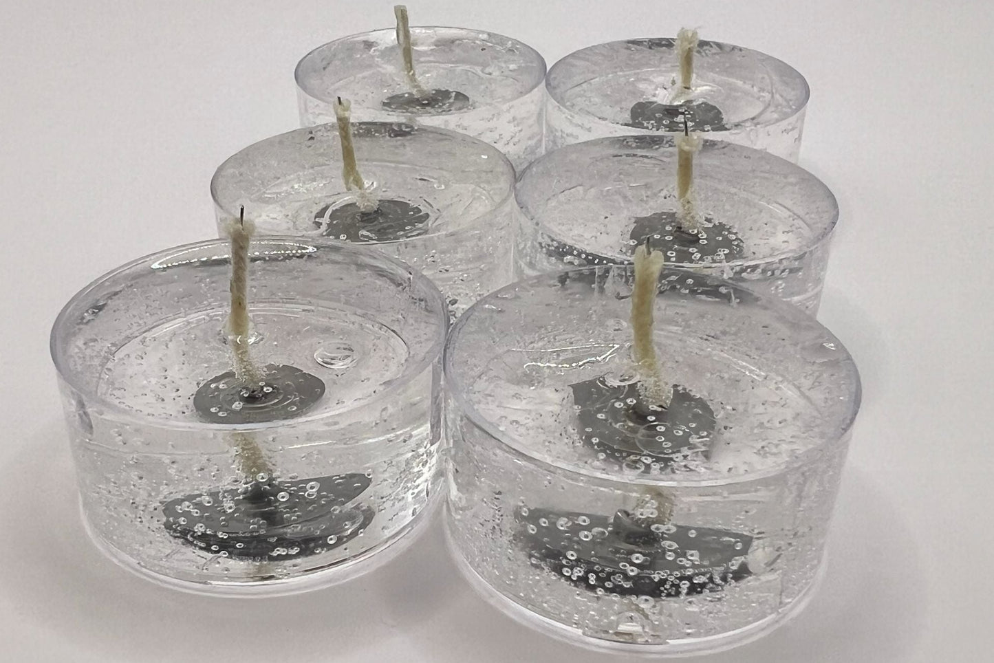 Set of six clear candles with visible wicks on a white background