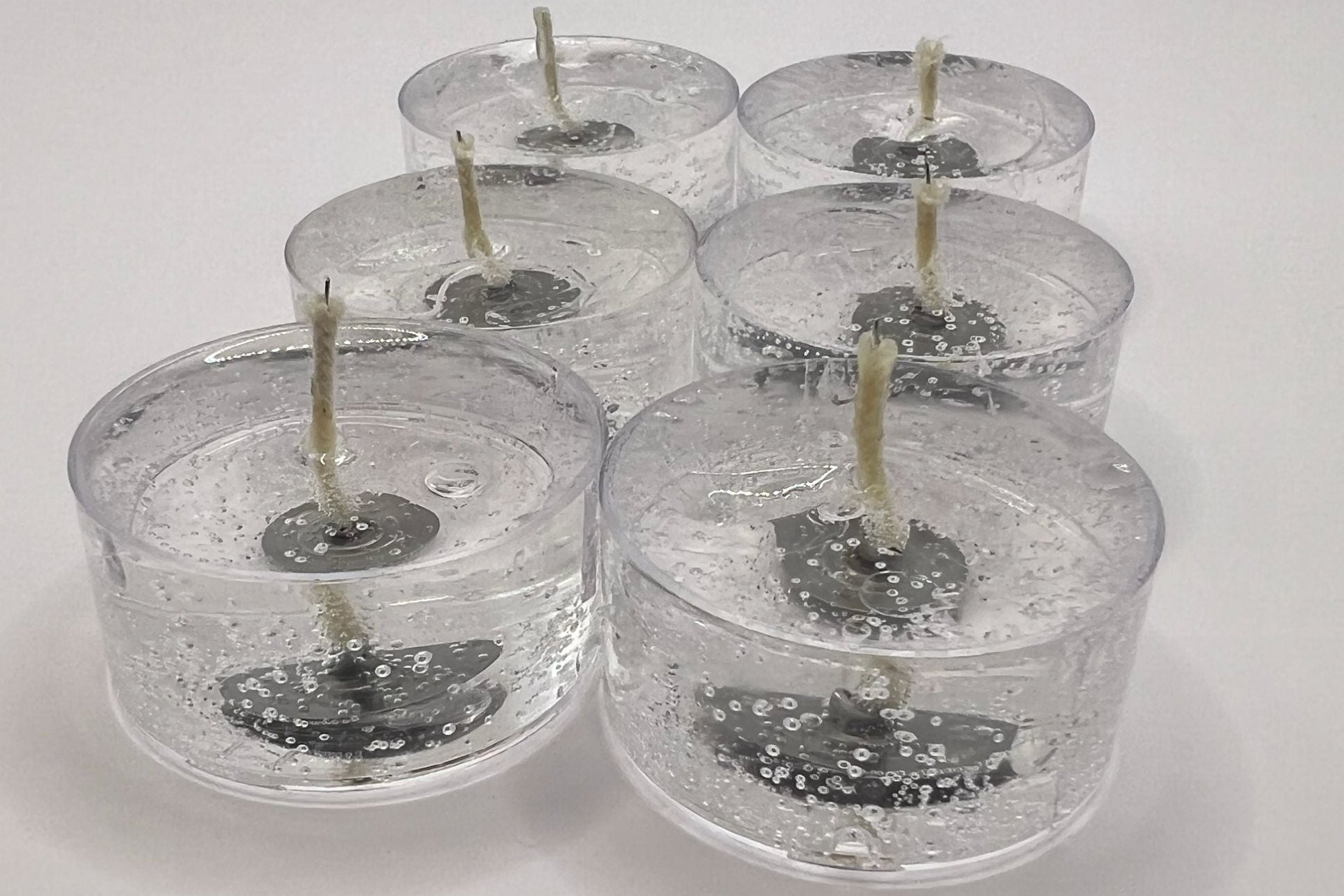 Set of six clear candles with visible wicks on a white background
